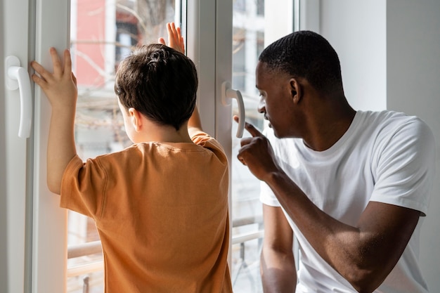 Jovem pai mostrando algo para o filho na janela