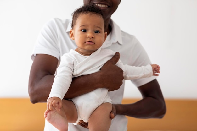 Foto jovem pai negro segurando bebezinho bonitinho nas mãos