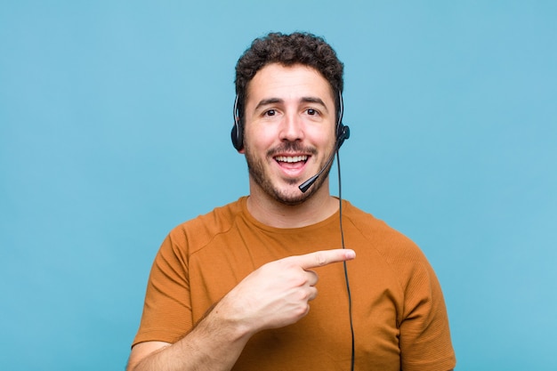 Jovem parecendo animado e surpreso apontando para o lado e para cima para copiar o espaço