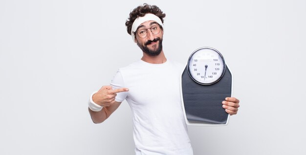 Jovem parecendo orgulhoso, confiante e feliz, sorrindo e apontando para si mesmo ou fazendo o primeiro sinal