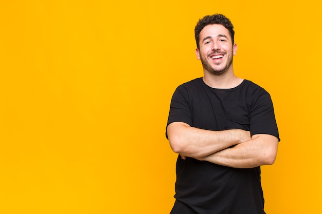 Jovem parecendo um empreendedor feliz, orgulhoso e satisfeito, sorrindo com os braços cruzados