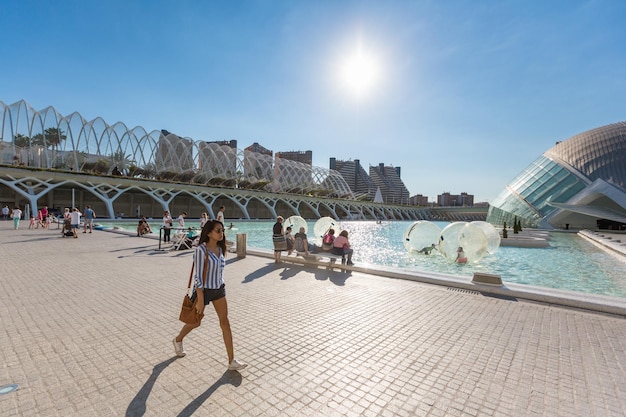 Jovem passa pela piscina com pessoas relaxantes na cidade das artes e ciências em Valência, Espanha