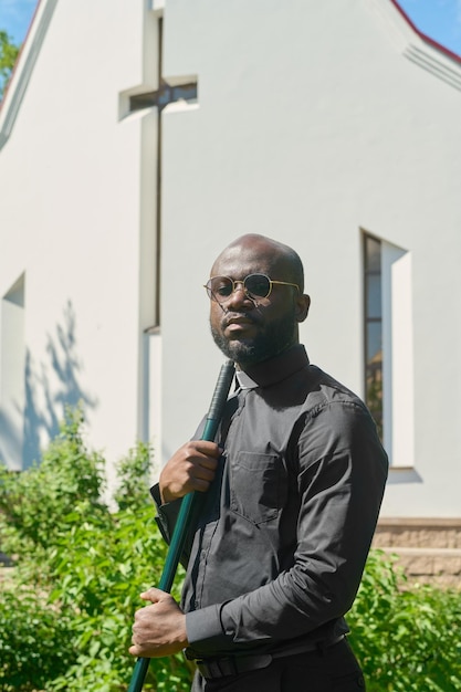 Jovem pastor sério da etnia afro-americana segurando a ferramenta de trabalho