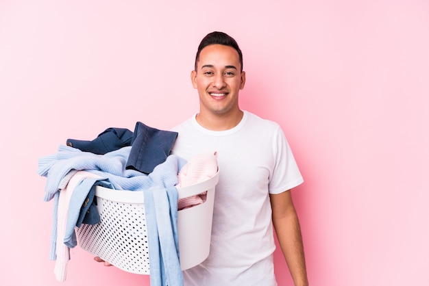 Jovem pegando roupas sujas isoladas feliz, sorridente e alegre