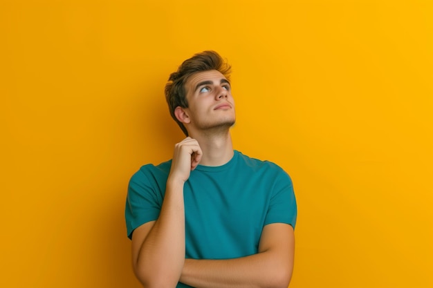 Foto jovem pensativo de camisa turquesa profundamente em contemplação em fundo amarelo