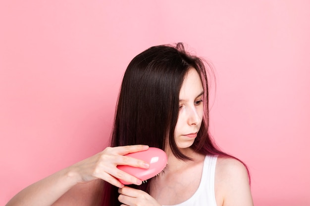 Jovem penteando o cabelo com pente rosa