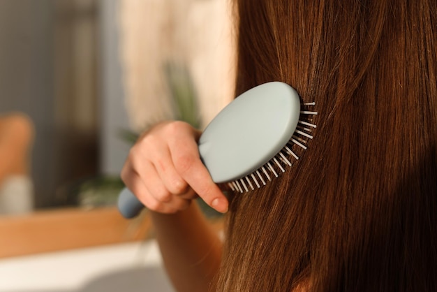 Jovem penteando o cabelo depois de aplicar uma máscara no banheiro. Cuidados com os cabelos, rotina matinal, conceito de desperdício zero ecologicamente correto.