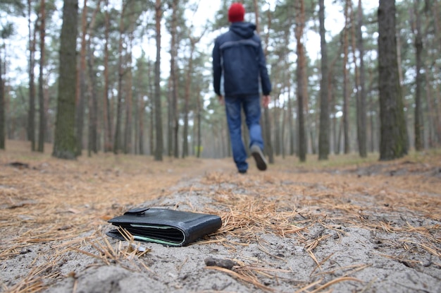 Jovem perde sua bolsa com notas de euro no caminho de madeira de abeto de outono russo Descuido e conceito de carteira perdida
