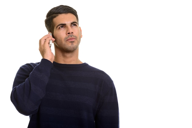 Jovem persa bonito falando no celular enquanto pensa