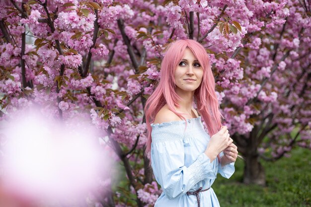 Jovem perto da árvore florescendo de sakura Flores cor de rosa primavera e conceito de juventude Menina elegante sorrindo Jardim florescente com cerejeira Lugar de cópia para texto