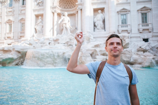 Jovem perto da fonte fontana di trevi com moedas nas mãos