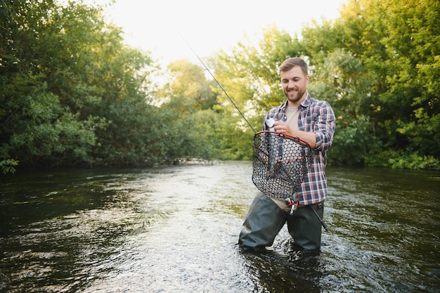 Jovem pesca com mosca ao nascer do sol