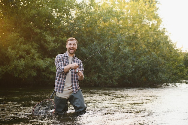 Jovem pesca com mosca ao nascer do sol