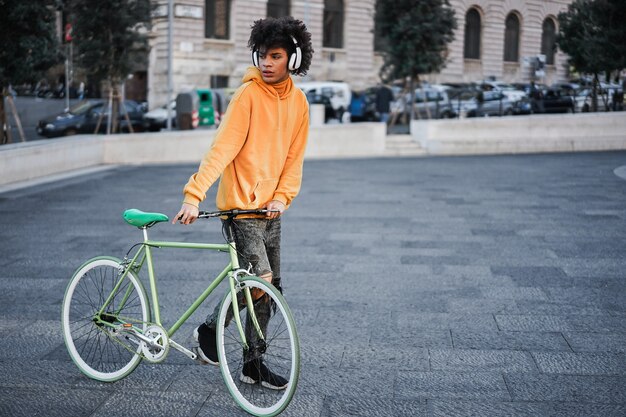 Jovem piloto africano se divertindo ouvindo música pela cidade - concentre-se nas mãos segurando uma bicicleta