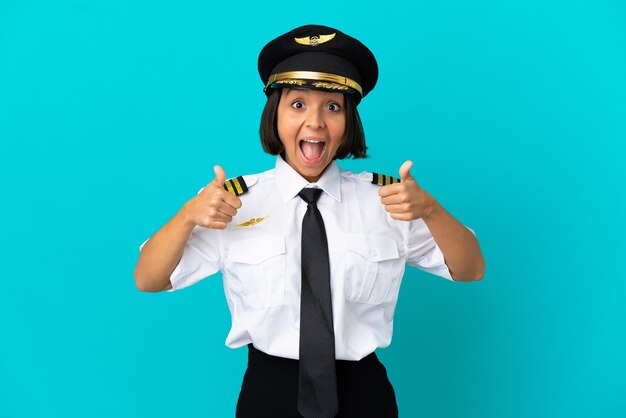 Jovem piloto de avião sobre fundo azul isolado fazendo um gesto de polegar para cima