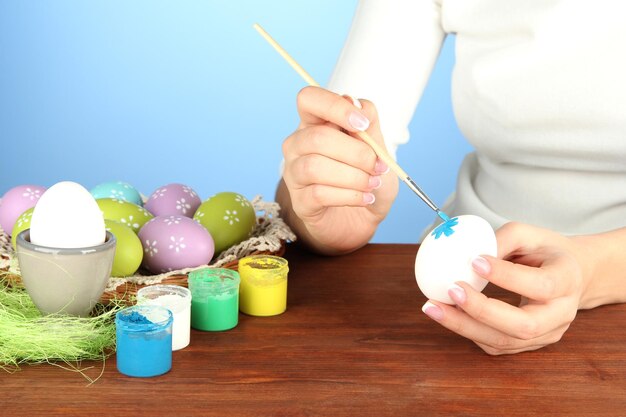 Jovem pintando ovos de Páscoa na cor de fundo