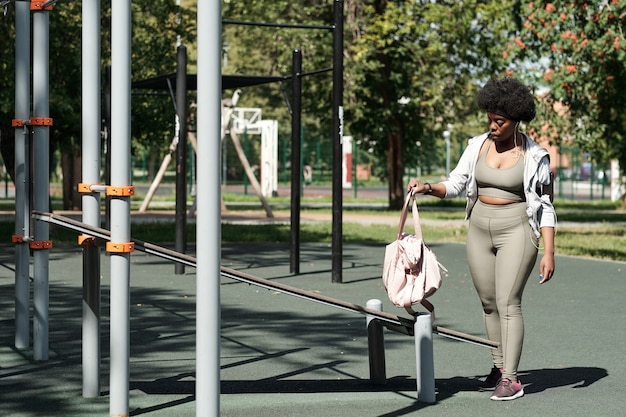 Jovem plus size feminina em roupas esportivas colocando bolsa nas instalações