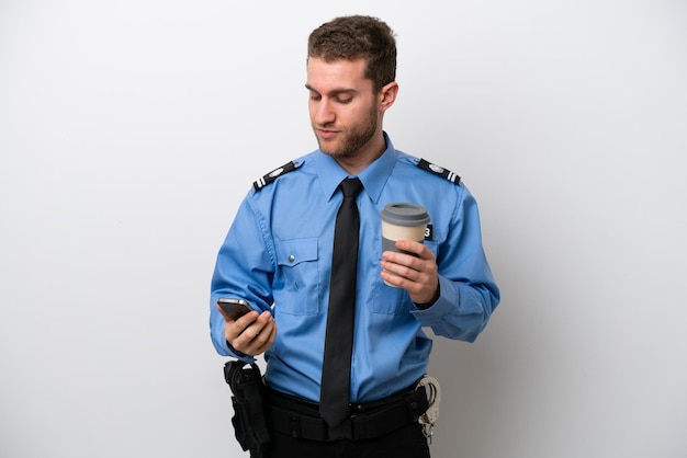 Jovem policial caucasiano isolado em fundo branco segurando café para levar e um celular