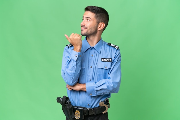 Foto jovem policial caucasiano sobre fundo isolado, apontando para o lado para apresentar um produto