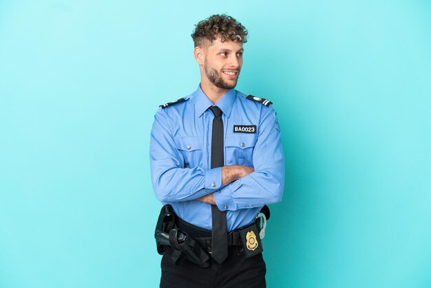 Jovem policial loiro isolado branco sobre fundo azul feliz e sorridente