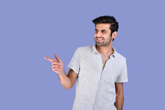 Jovem posando na frente com roupas de verão apontando para o lado com um sorriso modelo indiano do Paquistão