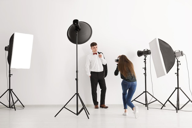 Jovem posando para fotógrafo profissional em fundo branco no estúdio