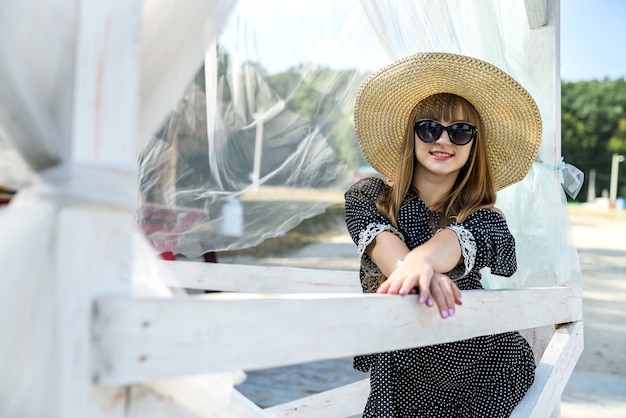 Jovem posando para o verão perto do lago no gazebo branco