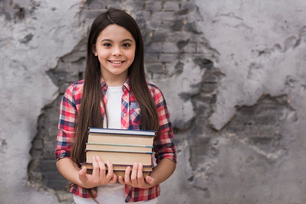 Jovem positiva close-up, segurando uma pilha de livros