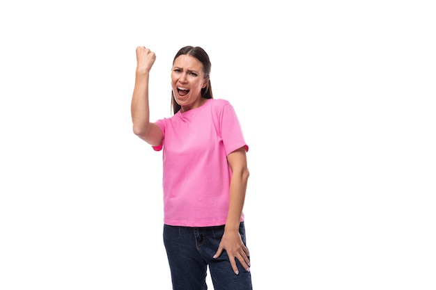 Jovem positiva mulher bonita com cabelo preto vestida com uma camiseta rosa se alegra em ganhar