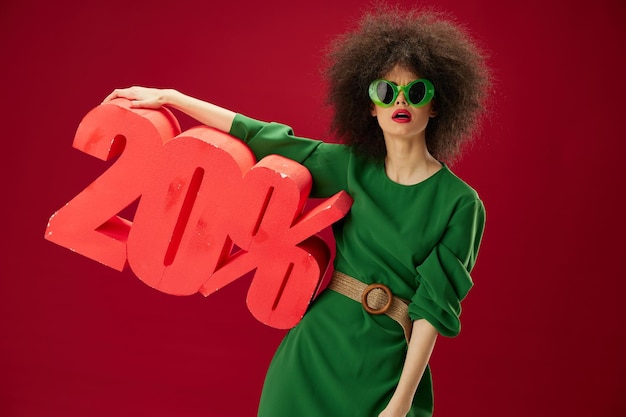 Foto jovem positiva vestido verde penteado afro óculos escuros vinte por cento nas mãos modelo de estúdio inalterado