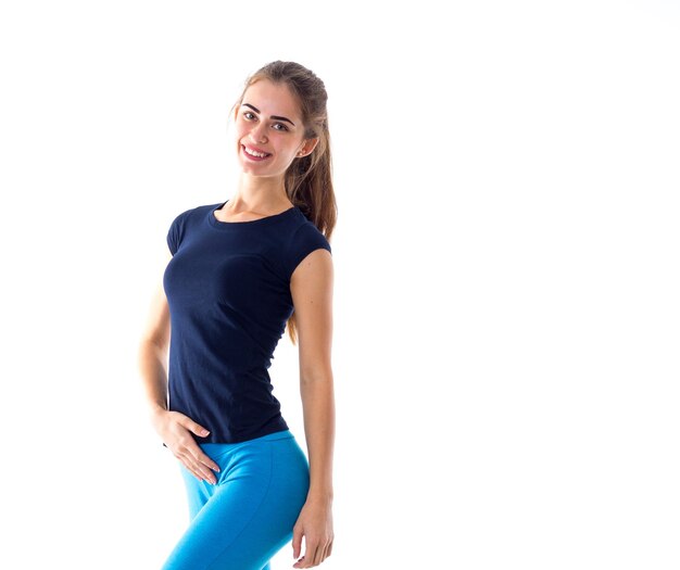 Jovem positiva vestindo camiseta azul e leggings em fundo branco no estúdio