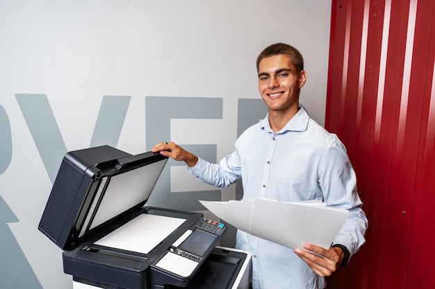 Foto jovem positivo usando impressora no escritório moderno