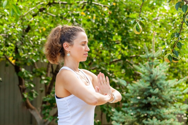 Jovem pratica ioga no jardim de verão Namaskar Mudra