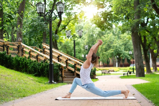 Jovem pratica ioga no parque. Asanas de ioga no parque da cidade, dia ensolarado. Conceito de meditação, bem-estar e estilo de vida saudável