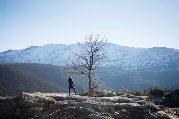 Jovem praticando caminhadas no Parque Nacional Sierra de Guadarrama, Segóvia e Madrid. Árvore solitária e pico Peñalara