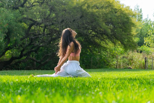 Jovem praticando ioga em um conceito verde ParkWellness