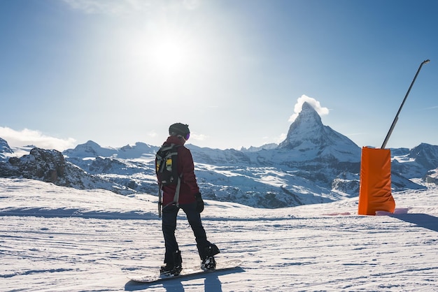 Jovem praticando snowboard na estância de esqui de zermatt, ao lado do famoso pico de matterhorn