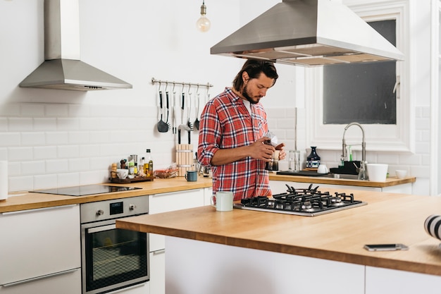 Foto jovem preparando café na cozinha moderna