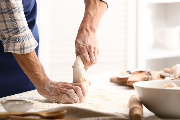 Jovem preparando massa para pão na cozinha