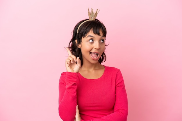 Jovem princesa mestiça com coroa isolada em fundo rosa com a intenção de realizar a solução enquanto levanta um dedo