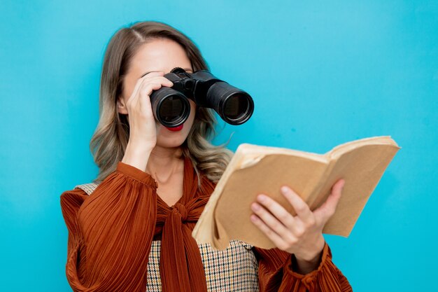 Jovem professora com livros e binóculos em azul