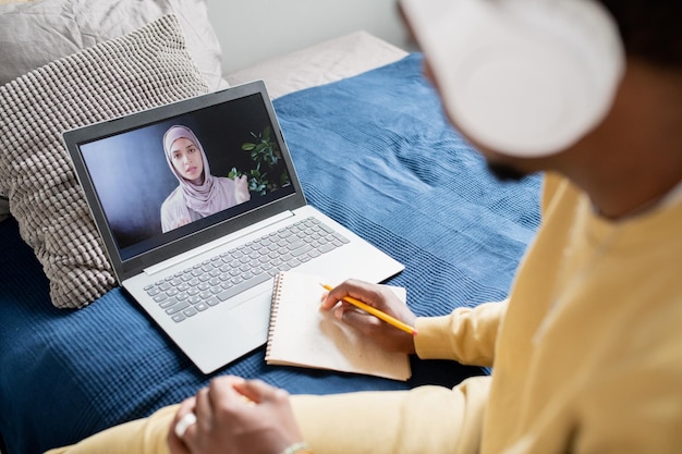 Foto jovem professora confiante em hijab, explicando o ponto da aula para o aluno