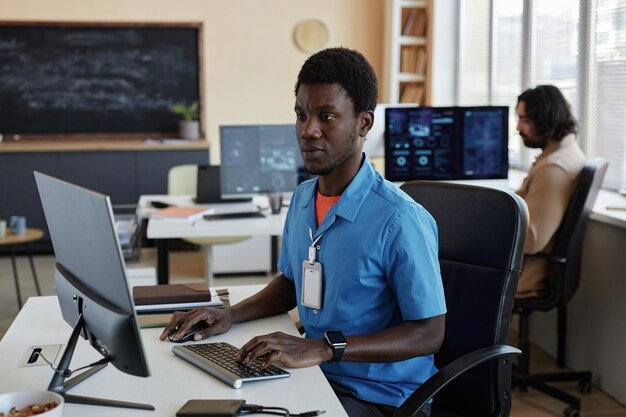 Jovem programador afro-americano sério sentado na frente do computador