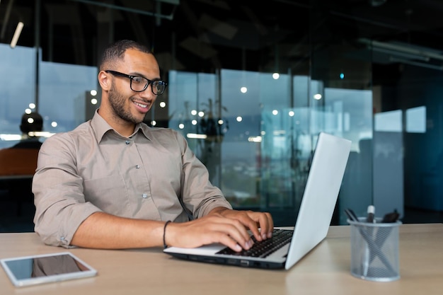 Jovem programador indiano de sucesso trabalhando dentro de uma empresa de desenvolvimento moderno usando laptop para