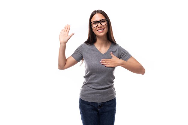 Jovem promotora mulher com óculos vestida com uma camiseta cinzenta ativamente gestos com as mãos para