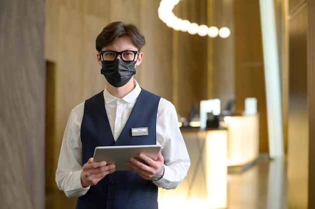 Foto jovem proprietário de hotel de luxo com tablet digital olhando para a câmera