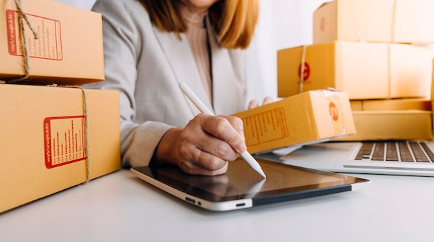 Jovem proprietário de uma pequena empresa fazendo compras on-line em casa, anotando os pedidos de clientes com telefones celulares, empresário de PME ou conceito de estilo de vida freelance