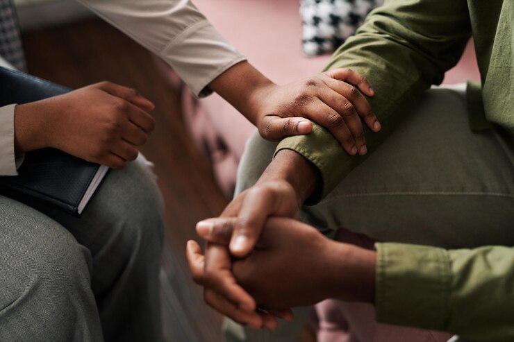 Foto jovem psicóloga afro-americana mantendo a mão do pulso do paciente do sexo masculino