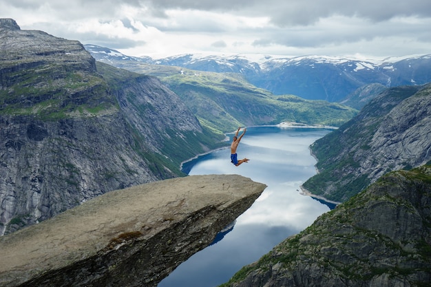 Jovem pula na borda Trolltunga. Noruega.