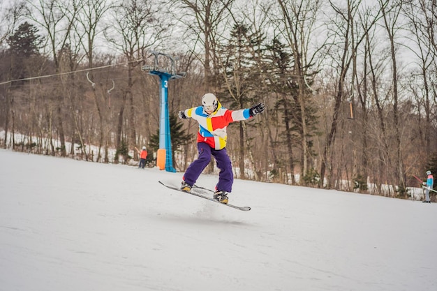 Jovem pulando com uma prancha de snowboard nas montanhas